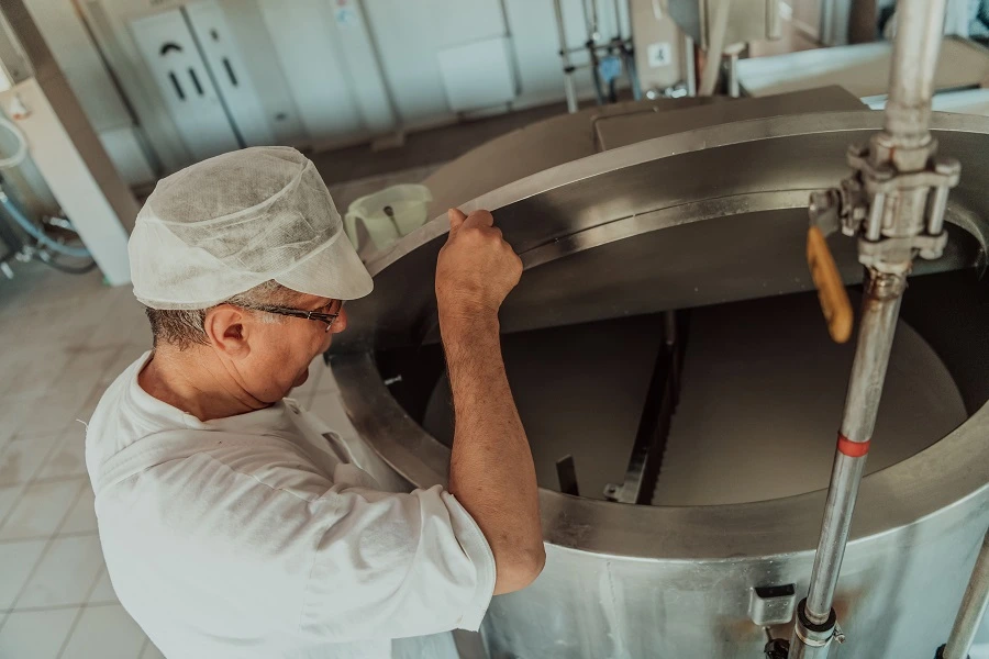 man looking inside milk fermenter equipment inside factory